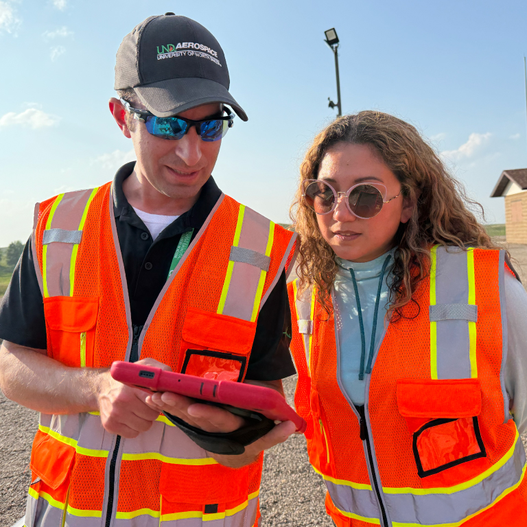 Two people in high-visibility vests looking at a tablet