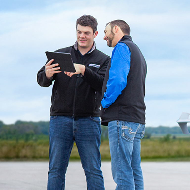 Two men in branded NPUASTS clothing viewing a tablet