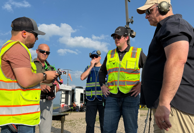 Several men standing in a group being briefed