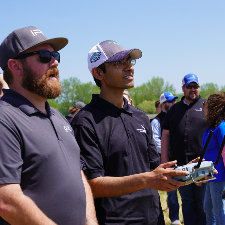 A man operating an unmanned vehicle as an onlooker stands nearby